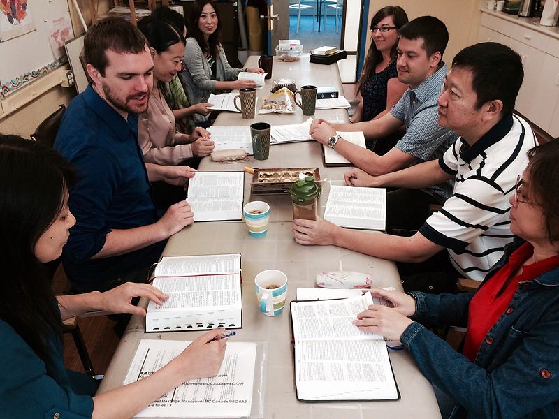 A group of adults studying the Bible together around a long table